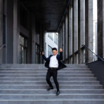 Happy and cheerful Asian businessman dancing near the office rejoices in victory and success